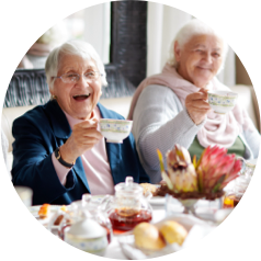 Elderly women enjoying tea together with pastries and flowers on the table